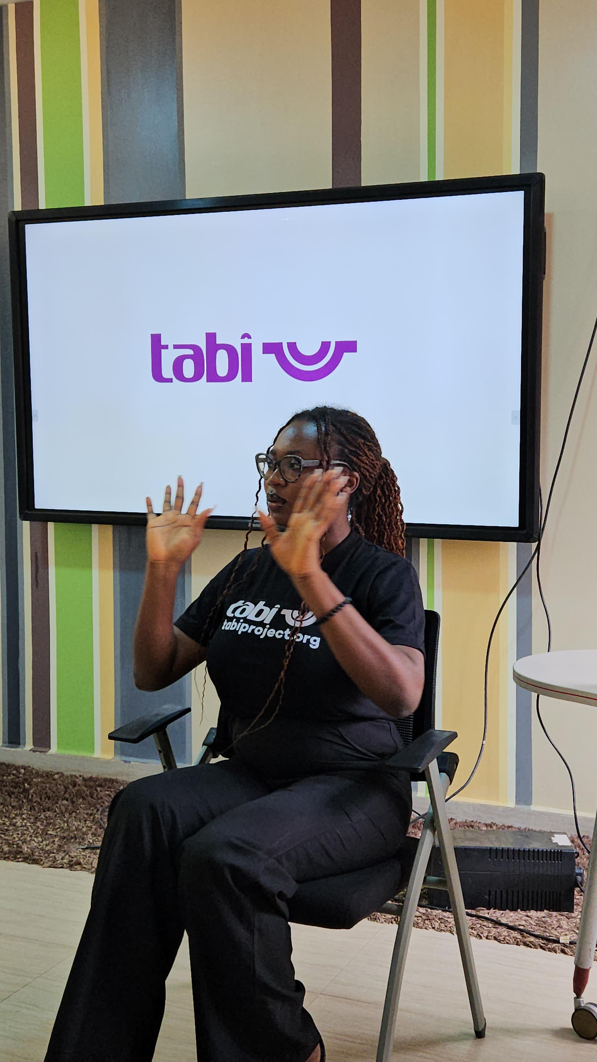 A woman smiling while typing code during a Tabi event